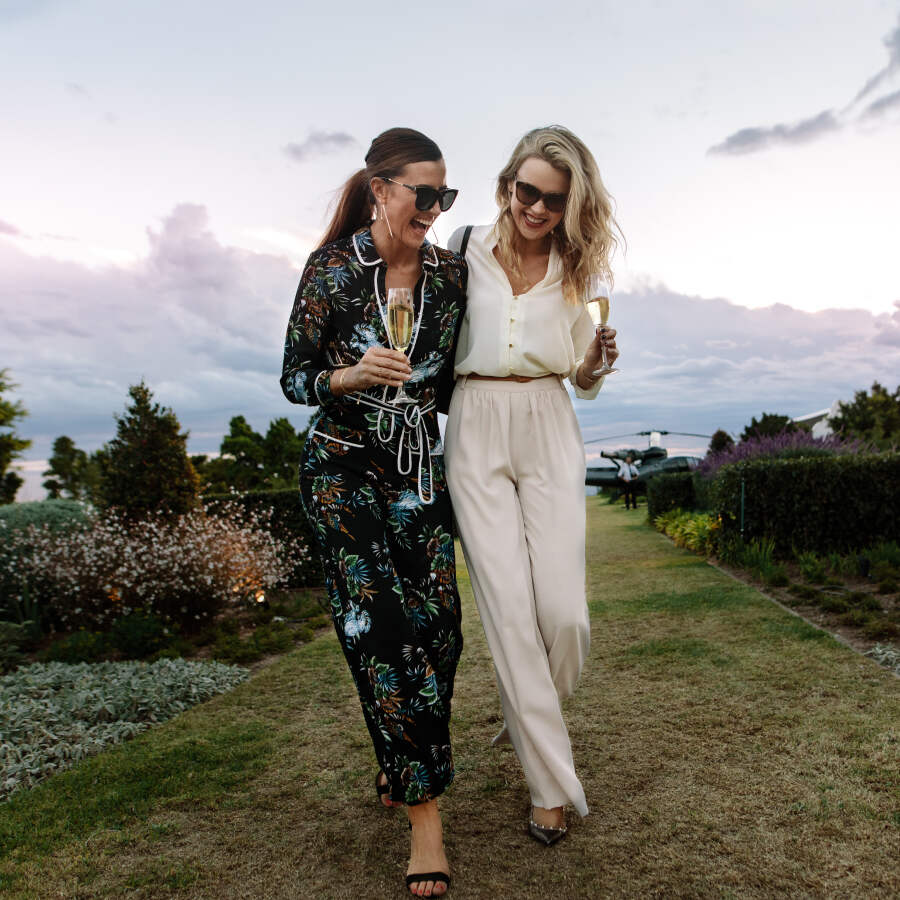 two women walking with glasses and laughing